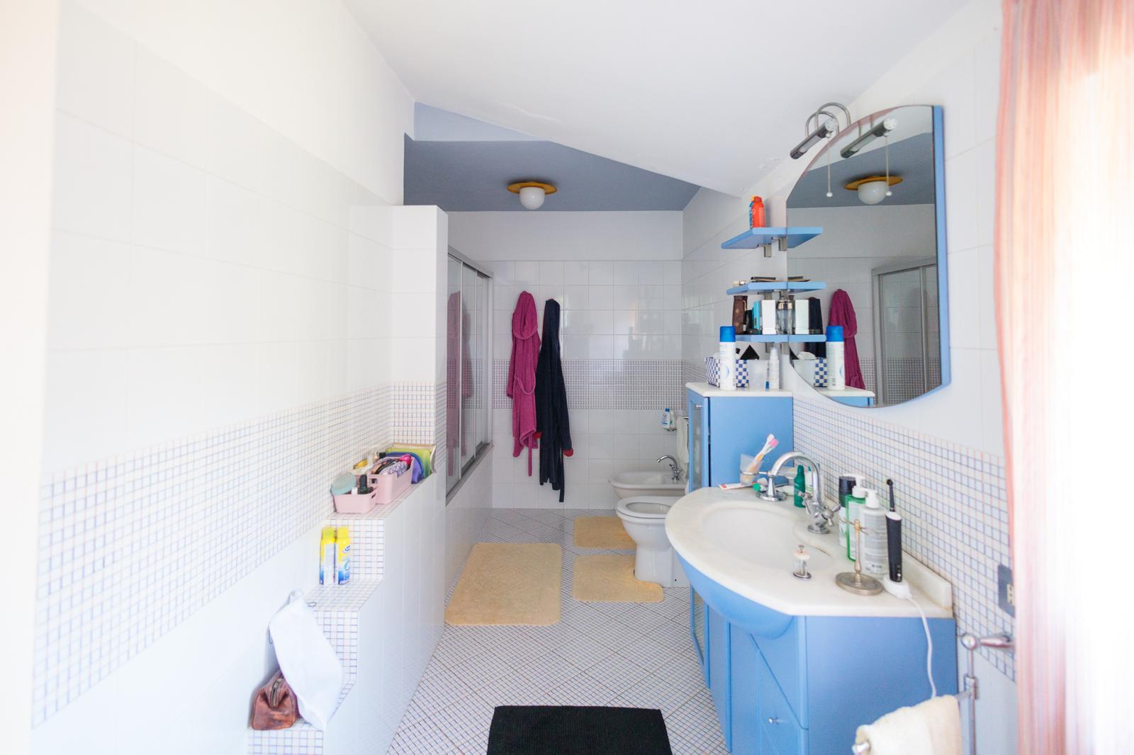 Bagno con mosaico blu, mobile moderno e zona doccia spaziosa