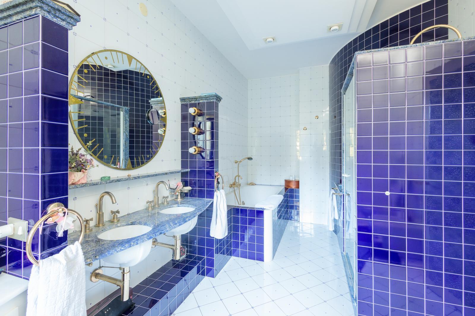 Bagno azzurro con mobile in legno, cabina doccia e rubinetteria classica