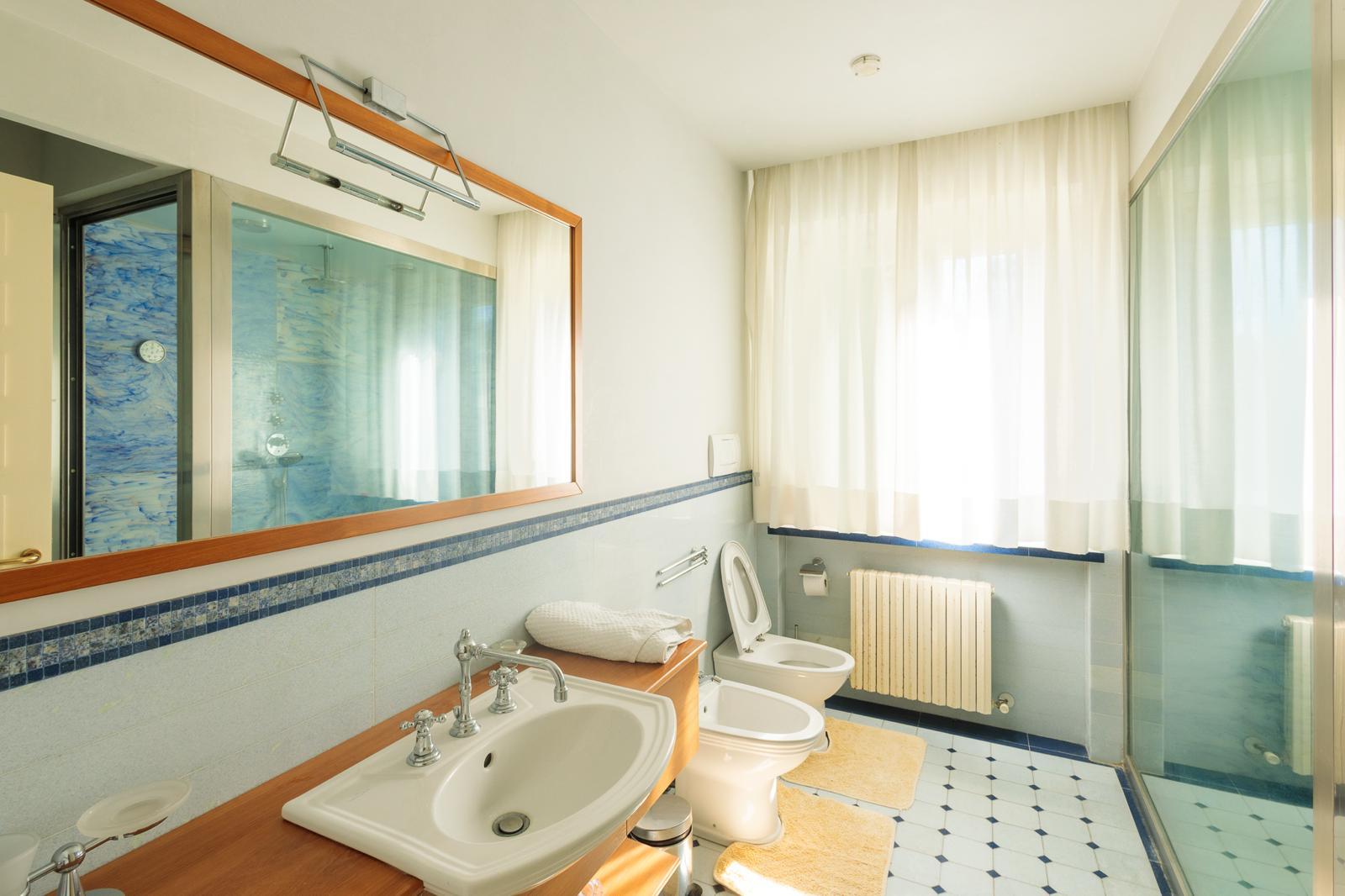 Bagno rosa con piastrelle bianche, accenti blu e vasca da bagno